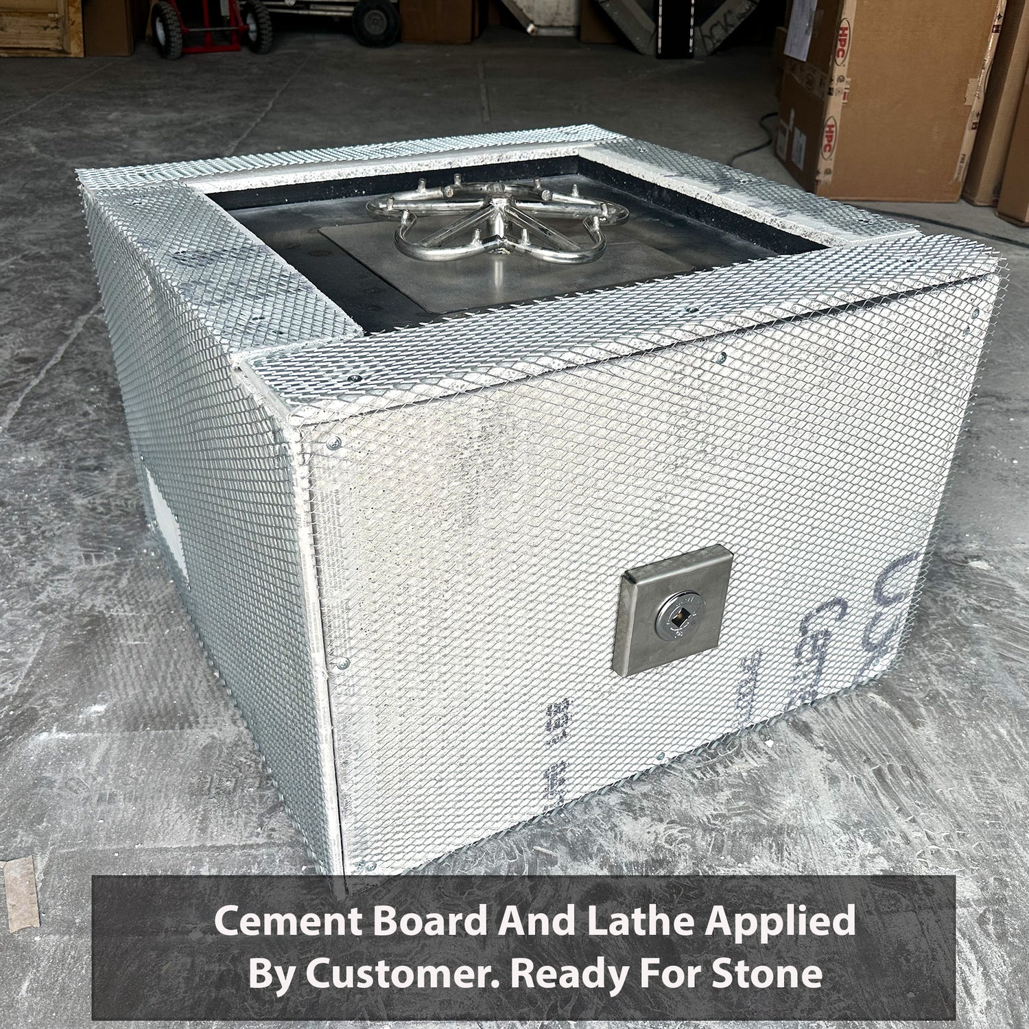 A custom square fire pit kit with a powder-coated steel frame, featuring a flat burner pan and a stainless steel burner ring, applied with cement board and lathe, ready for stone.