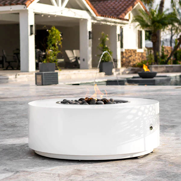 A white Unity Round Steel Gas Fire Pit 18" High (3 sizes) in an outdoor poolside patio.